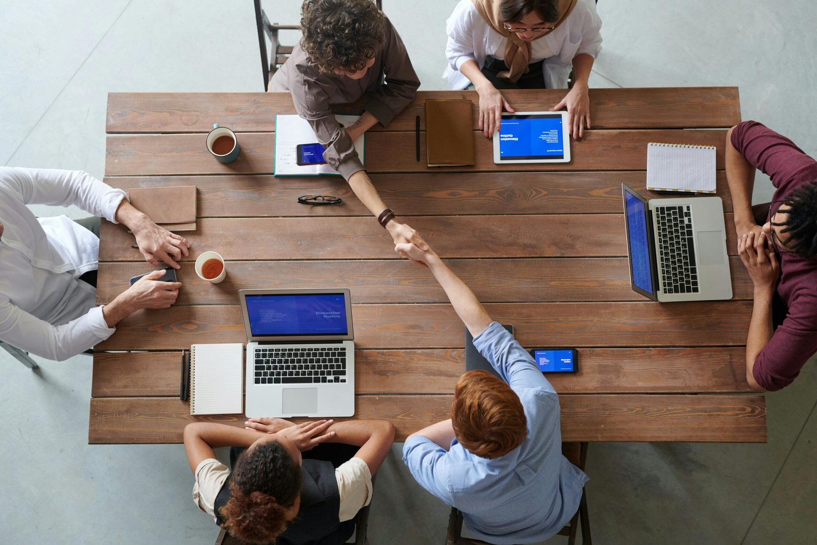 Home Overhead view of colleagues in a work meeting using laptops and tablets, emphasizing teamwork and technology.